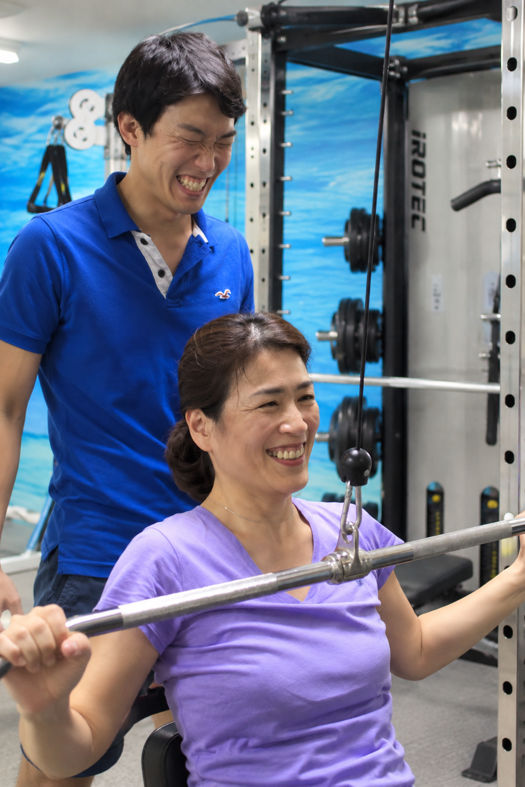 キャプテンジムで女性がトレーナーのサポートを受けながらトレーニングしている様子