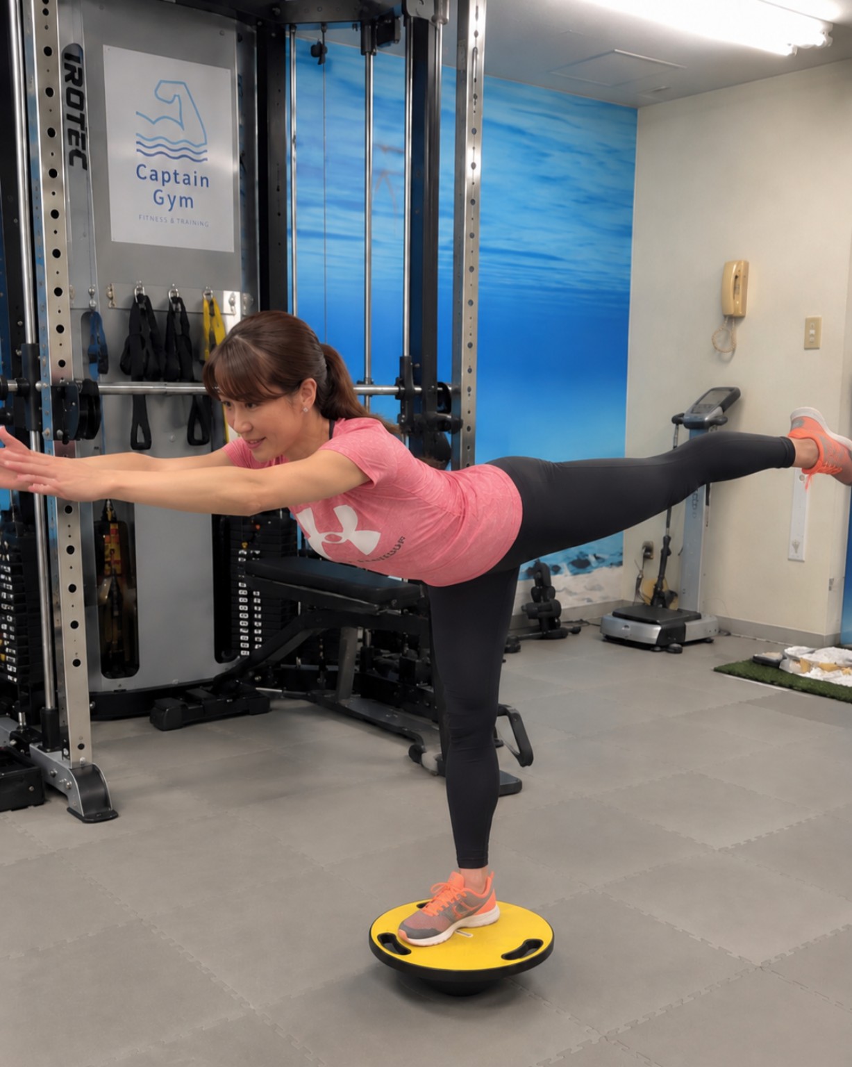 バランスボードの上で片脚バランストレーニングをする女性