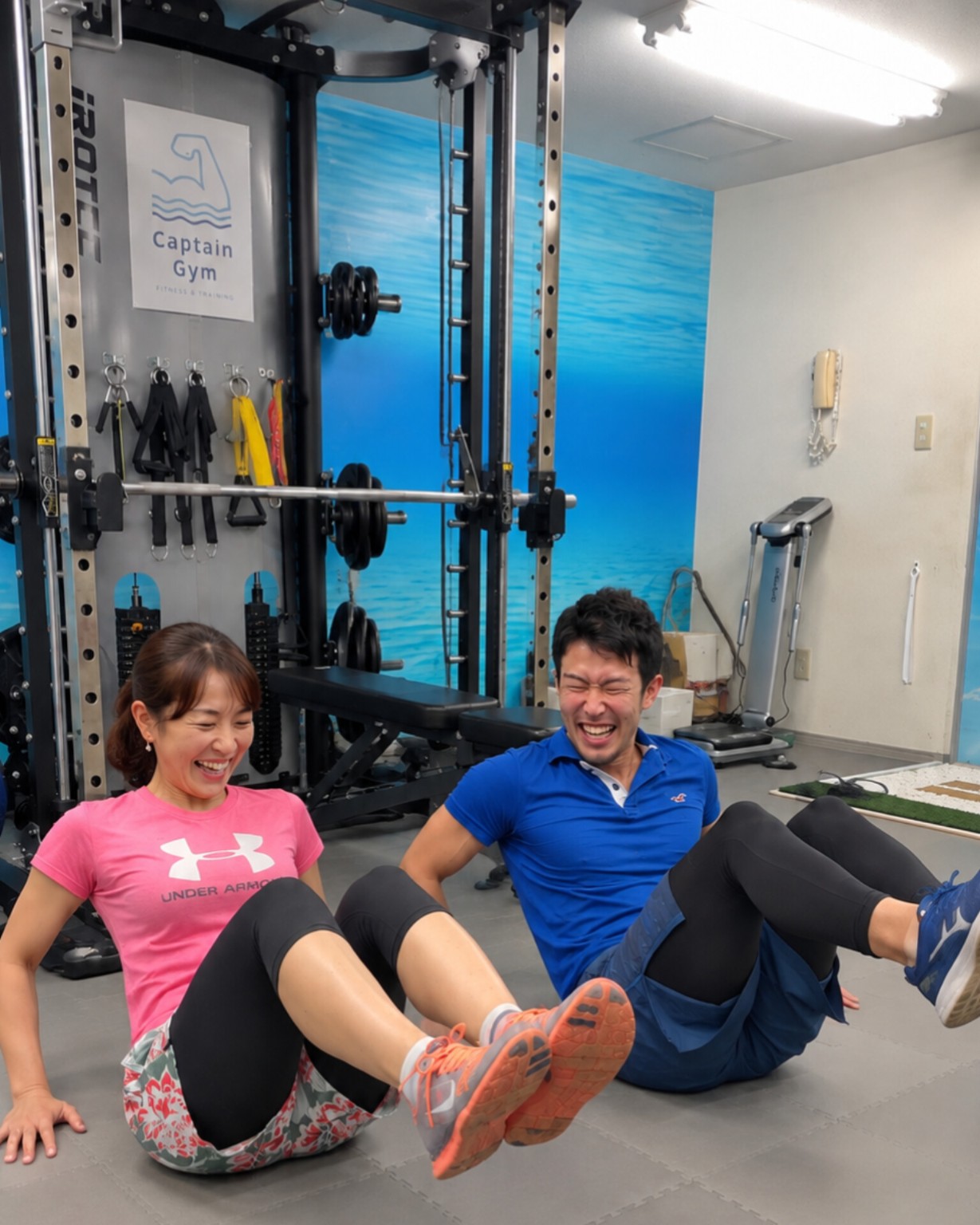 トレーナーと女性が笑顔で体幹トレーニングをする様子